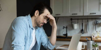 Man stressing over work on laptop at kitchen table