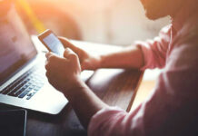 Person using a smartphone and laptop at desk