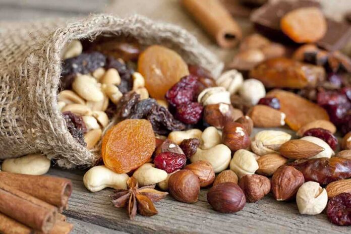 A burlap sack spilling a variety of nuts and dried fruits on a wooden table