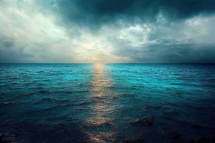 shutterstock_2212935531.jpg A serene ocean view with a dramatic sky and sunset reflection on the water