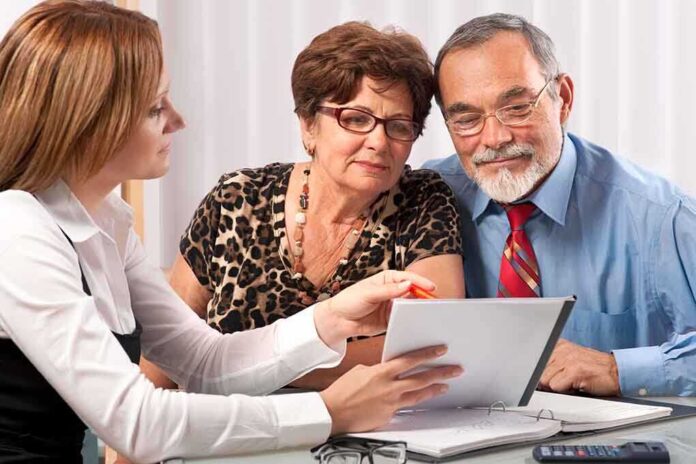 shutterstock_58006588.jpg A financial advisor discussing documents with an elderly couple