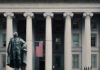 US Treasury Department building with statue and flag.