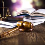 Massive $150M Legal Battle – Double Jeopardy Twist A gavel legal books and scales of justice on a wooden table