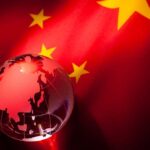 Chinese Takeover — 240 US Schools Under Control A globe illuminated against the backdrop of the Chinese flag