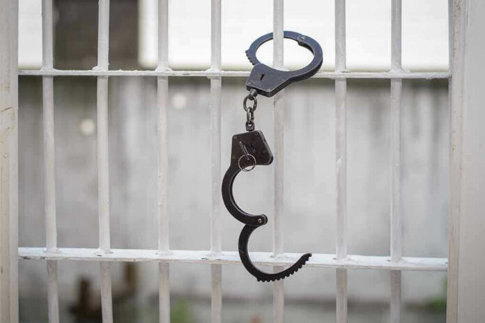 680970664 Handcuffs hanging on a barred window.