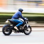 American Motorcycle Icon IMPLODING — Hundreds Shuttered A person riding a motorcycle swiftly through an urban area