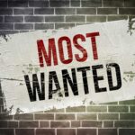 FBI MANHUNT Escalates — $50K Bounty Posted A weathered poster displaying the words MOST WANTED on a brick wall