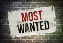 A weathered poster displaying the words MOST WANTED on a brick wall