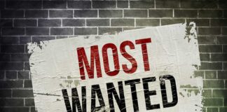 A weathered poster displaying the words MOST WANTED on a brick wall