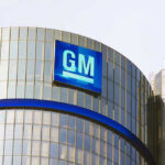 Glass building with large GM logo on top.