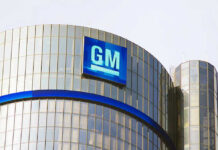 Glass building with large GM logo on top.