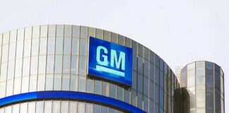 Glass building with large GM logo on top.