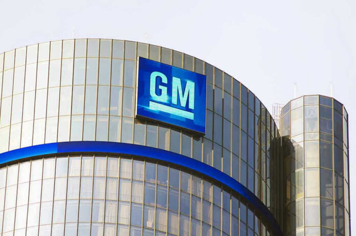 Glass building with large GM logo on top.