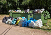 Overflowing garbage bins with bags on the ground.