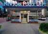 NYPD precinct building with signs on a city street