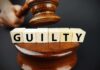 A gavel above wooden blocks spelling 'GUILTY'