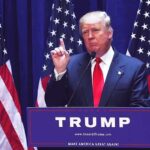 Donald Trump delivering a speech at a podium with American flags in the background