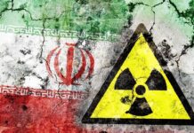 A cracked wall featuring the Iranian flag and a nuclear warning symbol