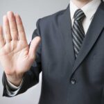 A man in a suit holding up his hand in a stop gesture