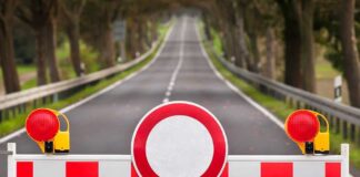 Traffic barrier with a red and white sign blocking a road