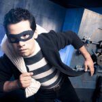 BIZARRE HEIST — What They TOOK A masked thief in a striped shirt holding a bag while emerging from a bank vault