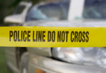 Yellow police tape in front of a car.