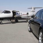 A private jet parked at an airport with a luxury car in the foreground