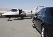 A private jet parked at an airport with a luxury car in the foreground