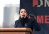 AOC passionately speaking at a podium during a rally