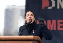 AOC Organizes Citizens to TRACK Federal Agents AOC passionately speaking at a podium during a rally