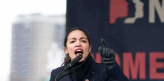 AOC passionately speaking at a podium during a rally