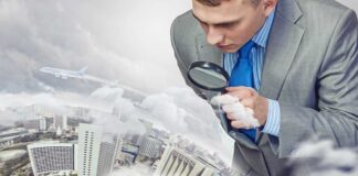 Businessman examining a cityscape with a magnifying glass amidst clouds and an airplane