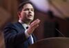 Standing Ovation Shocks Munich: What Rubio SAID A man in a suit delivering a speech at a podium