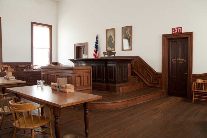 shutterstock_71233234.jpg Interior of a historic courtroom with wooden furniture and an American flag