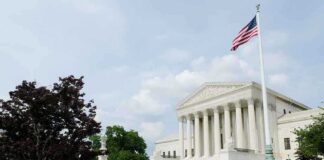 The U.S. Supreme Court building with an American flag and landscaped grounds