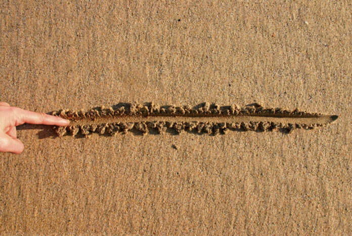 2360943 Finger drawing line in wet sand beach
