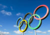 IOC Releases NEW ELIGIBILITY Rules For WOMEN Olympic rings sculpture against blue sky.