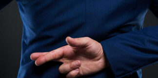 Crossed fingers behind back in blue suit.