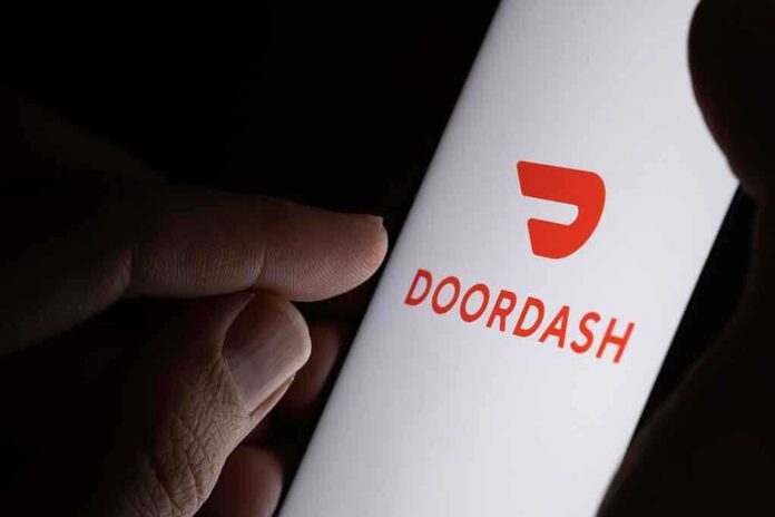 A hand holding a smartphone displaying the Doordash logo