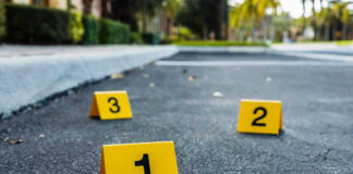 Crime scene markers on asphalt with bullet casing.