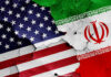 Iran TV BOUNTY Ignites Pilot Manhunt Cracked American and Iranian flags painted on a wall.