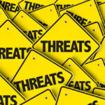 Top Judge Explodes–Media “Threatens Democracy Itself” Yellow warning signs with the word THREATS.