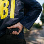 JOURNALIST BURNS Source — FBI Strikes FAST FBI agent holding a gun behind the back.