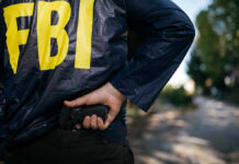 JOURNALIST BURNS Source — FBI Strikes FAST FBI agent holding a gun behind the back.