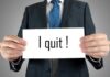 A man in a suit holding a sign that says I quit