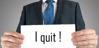 A man in a suit holding a sign that says I quit