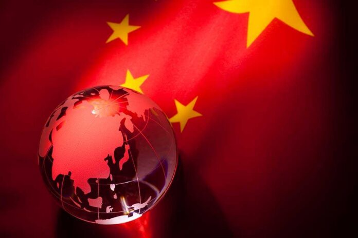 A globe illuminated against the backdrop of the Chinese flag