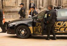 Cartel Ties? Senator’s Shocking Arrest Rumor Police officers standing and sitting near a patrol car.