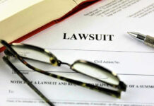 Lawsuit paperwork with glasses, pen, and an open book.