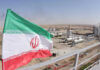 Nuclear Alarm: IRGC-Linked Outlet Urges Iran to Build the Bomb Iranian flag near an industrial gas refinery.
